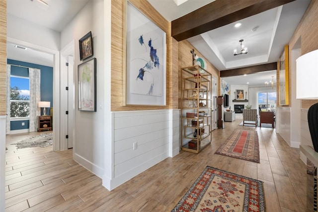 hallway featuring visible vents, beam ceiling, wood finished floors, baseboards, and a chandelier