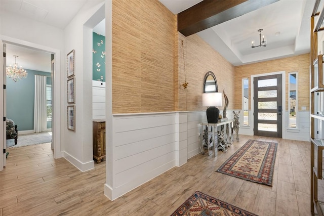 entrance foyer featuring beam ceiling, an inviting chandelier, and wood finished floors