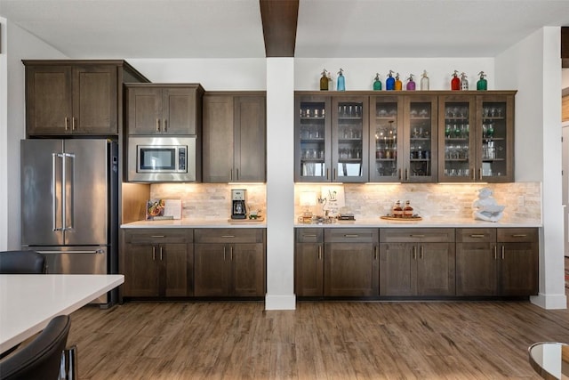 kitchen with dark brown cabinets, decorative backsplash, appliances with stainless steel finishes, and dark wood-style floors