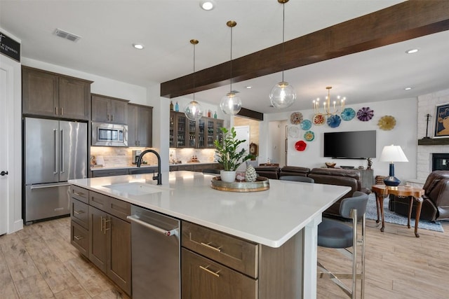 kitchen with visible vents, beam ceiling, a sink, dark brown cabinetry, and appliances with stainless steel finishes