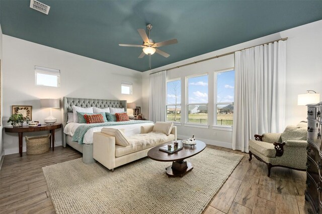 bedroom featuring a ceiling fan, wood finished floors, visible vents, and baseboards