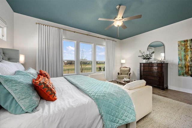 bedroom featuring a ceiling fan, baseboards, and wood finished floors