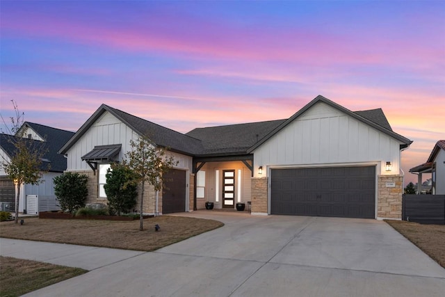 modern farmhouse style home with stone siding, a garage, board and batten siding, and driveway