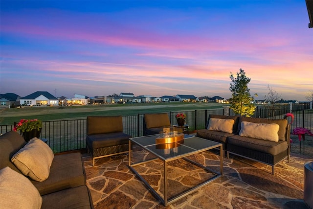 patio terrace at dusk with a residential view, outdoor lounge area, and fence