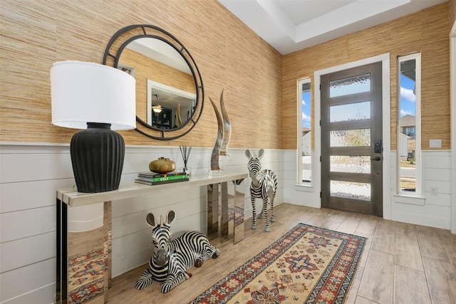 foyer entrance with wood finished floors, a healthy amount of sunlight, and wainscoting