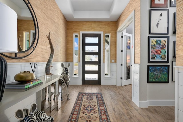 foyer featuring a tray ceiling, wood finished floors, and wainscoting