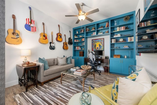 living room with ceiling fan, baseboards, and wood finished floors