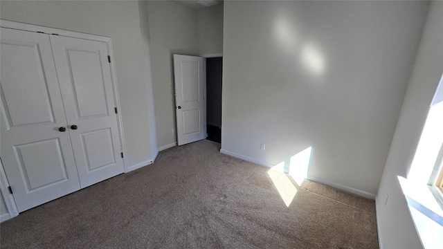 unfurnished bedroom with baseboards, carpet floors, and a closet