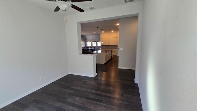 interior space with visible vents, baseboards, a ceiling fan, and dark wood-style flooring