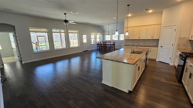 kitchen featuring visible vents, a ceiling fan, a sink, black gas stove, and decorative backsplash