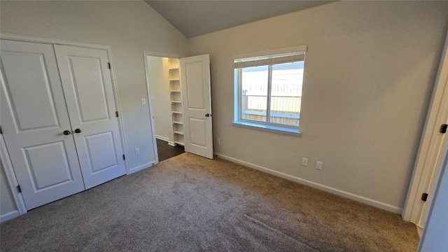 unfurnished bedroom with a closet, baseboards, carpet, and vaulted ceiling