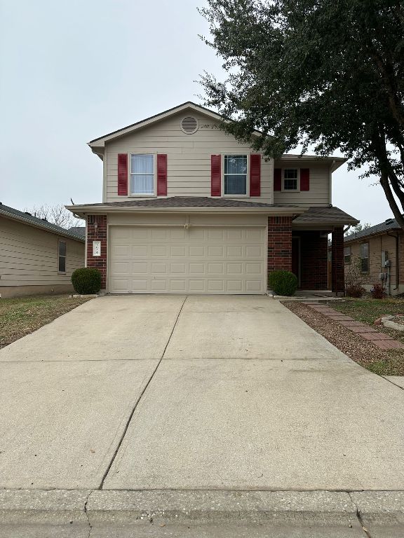 traditional-style home with brick siding, concrete driveway, and a garage