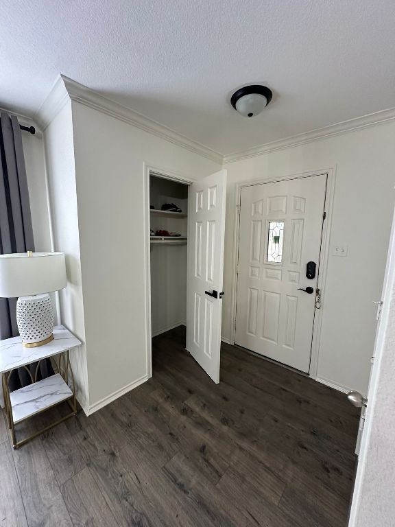 foyer featuring dark wood finished floors, crown molding, baseboards, and a textured ceiling