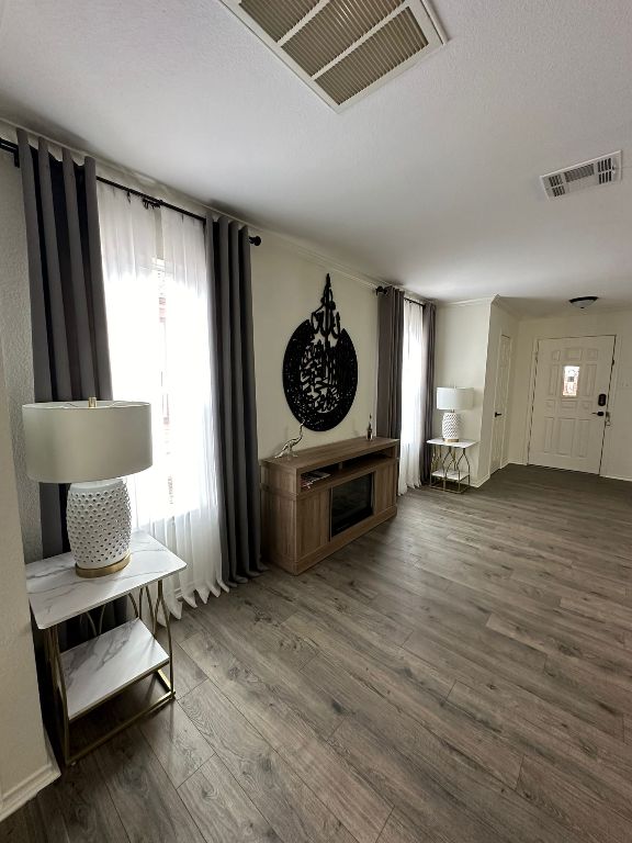 unfurnished living room with a wealth of natural light, visible vents, and wood finished floors