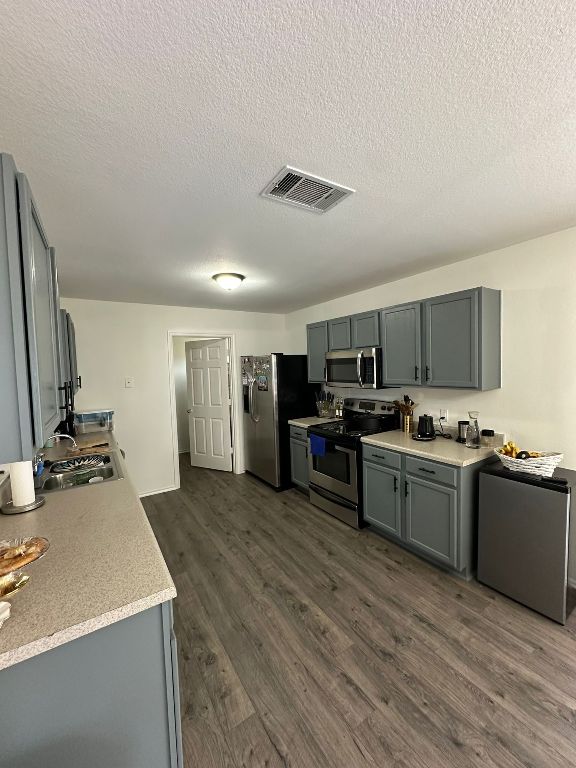 kitchen with visible vents, a sink, dark wood-type flooring, light countertops, and appliances with stainless steel finishes