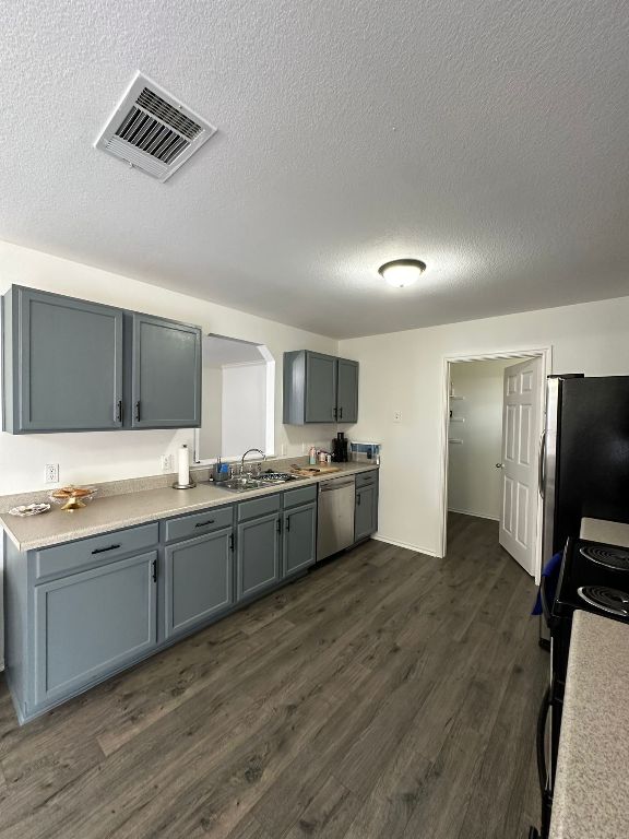 kitchen with visible vents, a sink, dark wood-style floors, appliances with stainless steel finishes, and light countertops