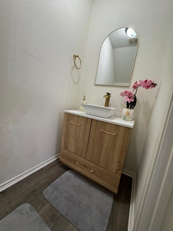 bathroom with vanity, visible vents, wood finished floors, and baseboards