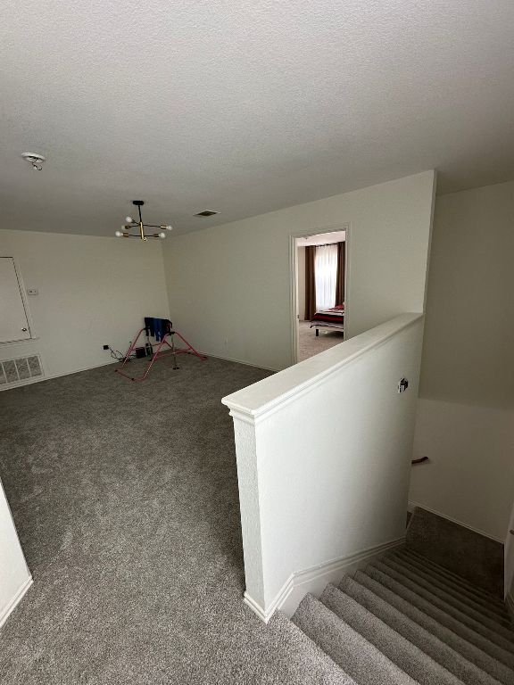 interior space featuring visible vents, carpet floors, and a textured ceiling