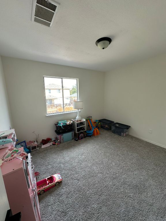 game room with carpet, visible vents, and a textured ceiling