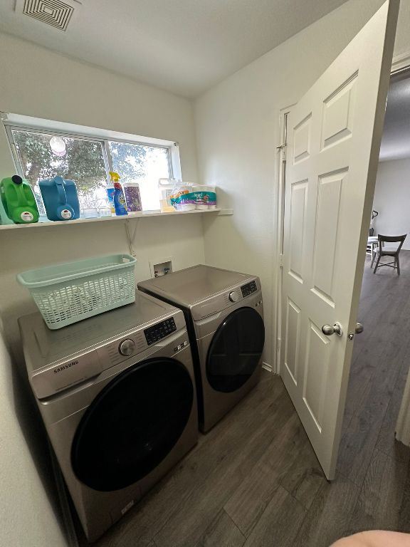 laundry area with visible vents, dark wood-style floors, laundry area, and washing machine and clothes dryer