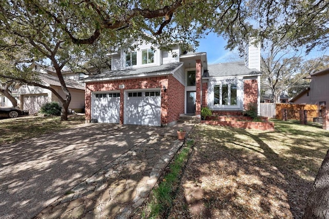 traditional-style house featuring driveway, fence, an attached garage, brick siding, and a chimney