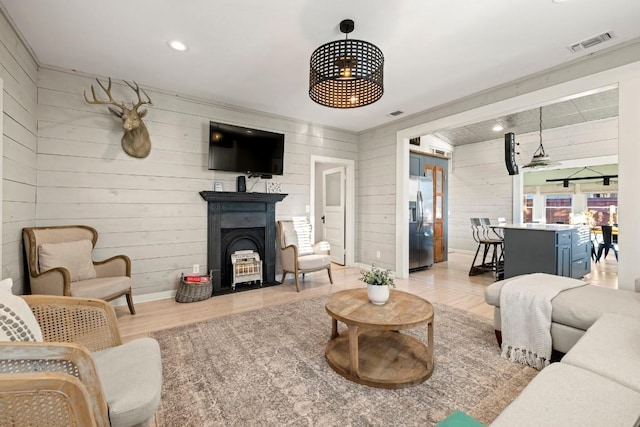 living area featuring recessed lighting, visible vents, wood walls, and wood finished floors