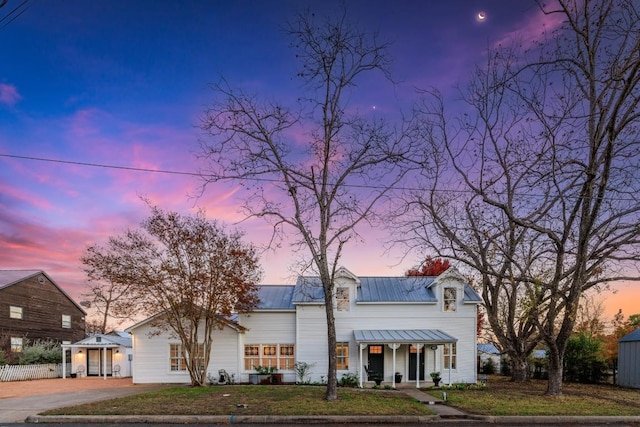 modern farmhouse with a yard, metal roof, concrete driveway, and a porch