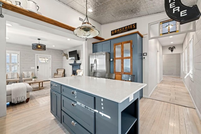 kitchen with open shelves, blue cabinets, stainless steel fridge with ice dispenser, and light wood-type flooring