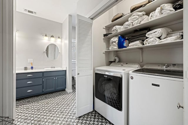 washroom with visible vents, washing machine and dryer, light floors, laundry area, and a sink