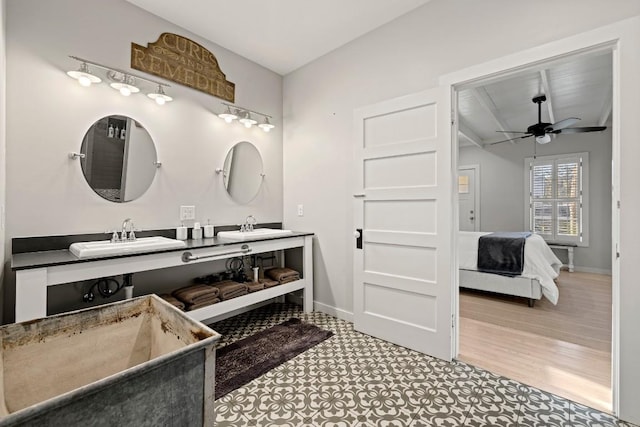 bathroom with baseboards, ensuite bathroom, a ceiling fan, and a sink