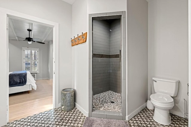 bathroom featuring toilet, ensuite bathroom, a ceiling fan, a tile shower, and baseboards