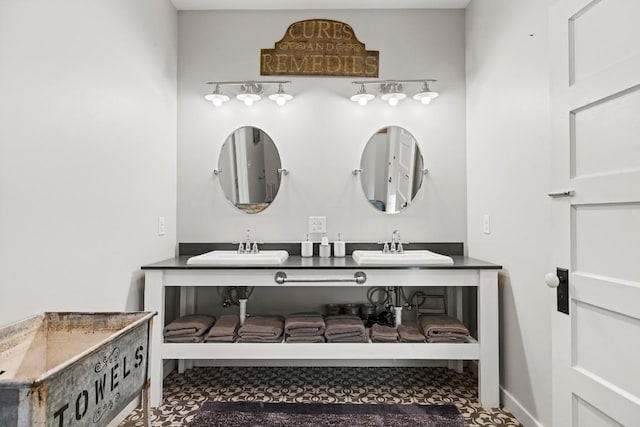 bathroom featuring double vanity, baseboards, and a sink