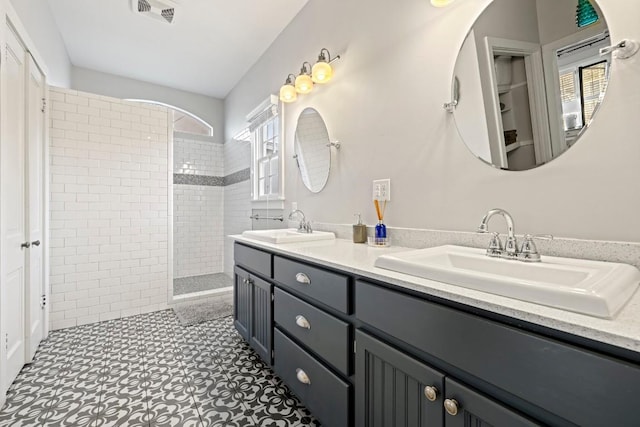 bathroom with a sink, visible vents, double vanity, and a walk in shower