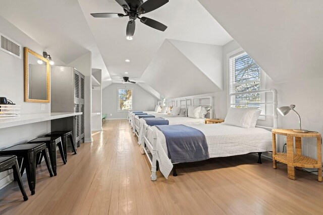 bedroom with a ceiling fan, visible vents, light wood finished floors, baseboards, and lofted ceiling