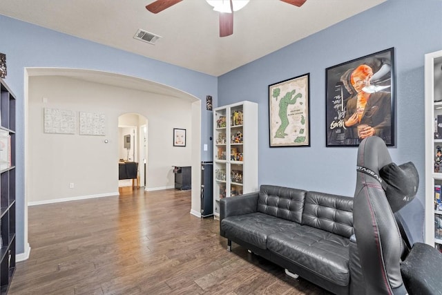 sitting room with visible vents, baseboards, wood finished floors, arched walkways, and a ceiling fan