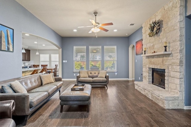 living area with visible vents, a ceiling fan, plenty of natural light, dark wood-style floors, and arched walkways