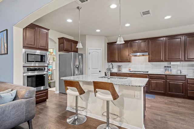 kitchen featuring tasteful backsplash, visible vents, under cabinet range hood, stainless steel appliances, and a sink