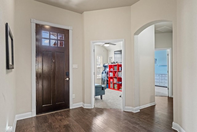 foyer with arched walkways, visible vents, baseboards, and dark wood-style flooring