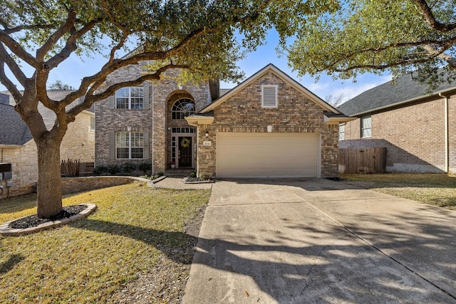 traditional home featuring brick siding, an attached garage, a front lawn, fence, and driveway