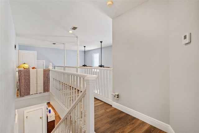 hall with baseboards, an upstairs landing, visible vents, and wood finished floors