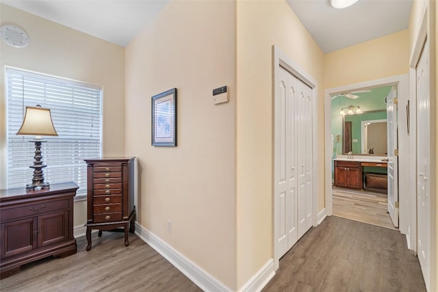 corridor featuring baseboards and light wood finished floors