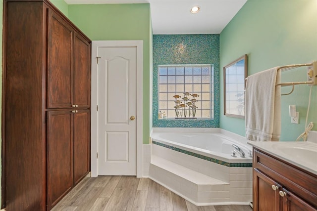 bathroom with vanity, a garden tub, and wood finished floors