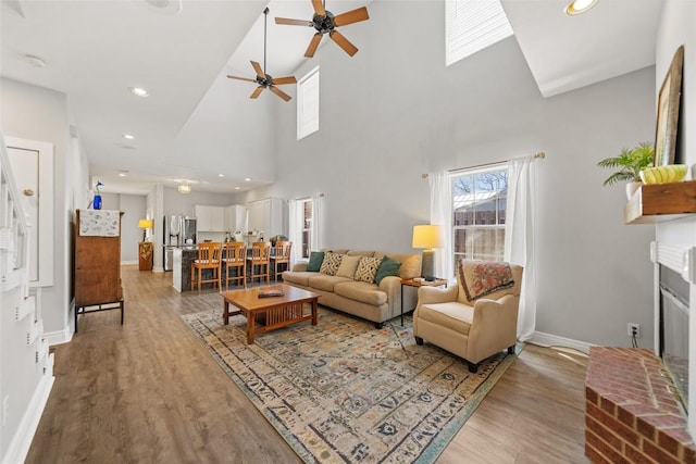 living area featuring light wood-style floors, baseboards, and ceiling fan