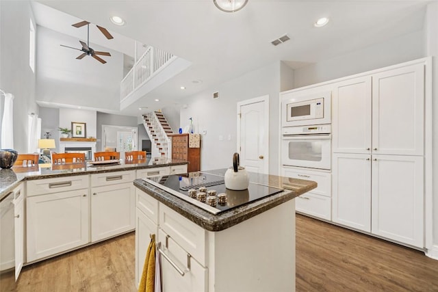 kitchen with white appliances, a ceiling fan, visible vents, light wood-style floors, and white cabinetry