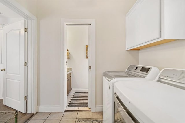 laundry room featuring light tile patterned flooring, cabinet space, baseboards, and washer and clothes dryer