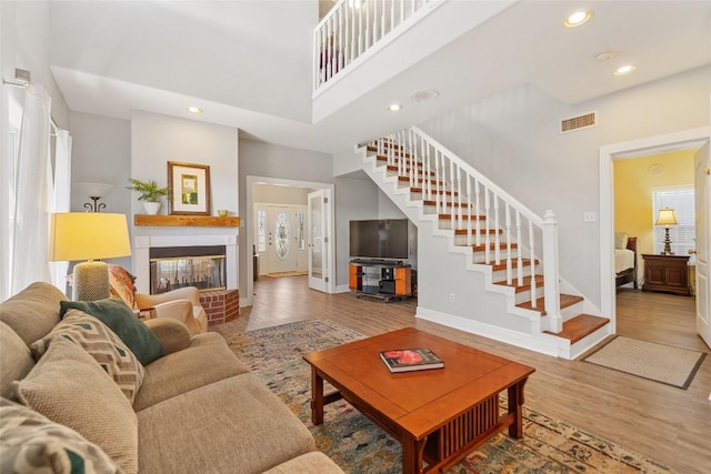 living area featuring stairway, wood finished floors, visible vents, a high ceiling, and recessed lighting