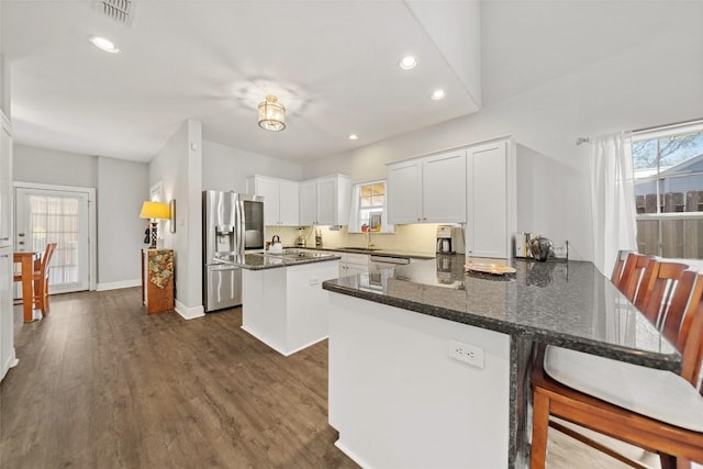 kitchen featuring visible vents, a sink, dark wood finished floors, stainless steel appliances, and a peninsula