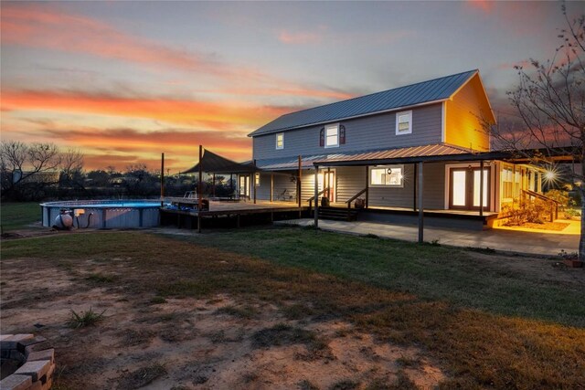 917 County Road 664, Devine, TX 78016 - rear view of house featuring metal roof, an outdoor pool, a lawn, and a patio area