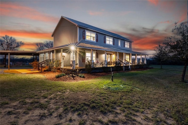 farmhouse with covered porch, metal roof, and a yard