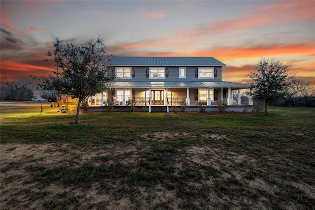 view of front of property featuring a porch, a front lawn, and metal roof